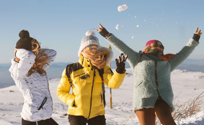Group of joyful adults playing in the snow, celebrating an active lifestyle after significant weight loss.